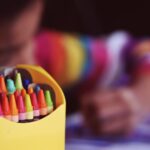 Crayons beside child coloring